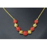 A pink coral bead necklet, comprising graduated coral beads each divided by 18ct yellow gold plain