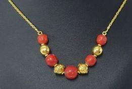 A pink coral bead necklet, comprising graduated coral beads each divided by 18ct yellow gold plain