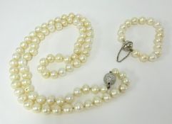 A long single row of 82 cultured pearls, (10-11mm), with a 14ct white gold diamond pave set ball