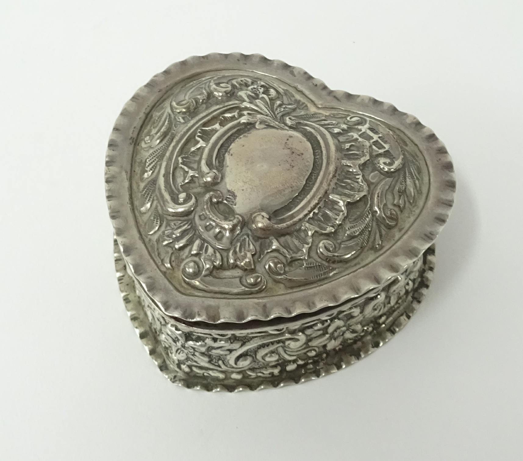 A George V silver box, heart shaped with embossed decoration.