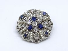 An 18ct white gold hand crafted designer brooch, consisting of a scallop circle pave set with a