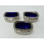 Three Victorian silver sarcophagus shaped table salts with blue glass liners