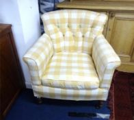 An Edwardian upholstered armchair with mahogany turned legs and brass casters.