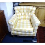 An Edwardian upholstered armchair with mahogany turned legs and brass casters.