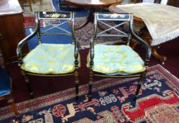 A pair of reproduction Regency style black lacquer and gilt framed elbow chairs with cane seats