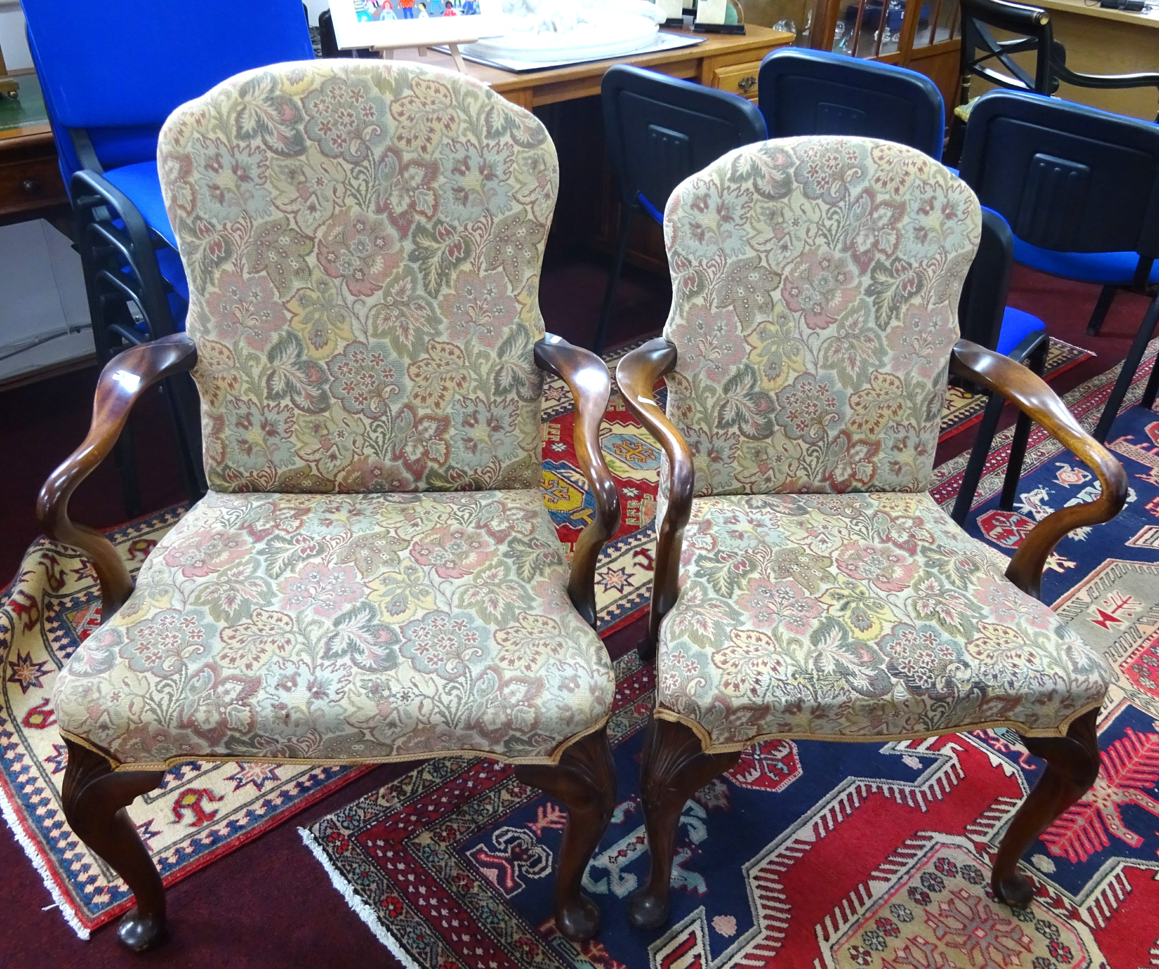 A pair of mahogany framed elbow chairs with upholstered seats and backs of Georgian design.