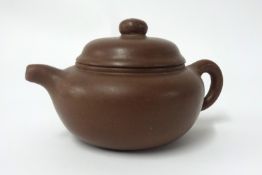 A Yixing small dark brown, plain teapot of squat form, height 7cm.