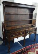 An antique oak two part dresser, the upper section fitted with shelves and four spice drawers, the