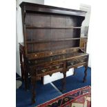 An antique oak two part dresser, the upper section fitted with shelves and four spice drawers, the
