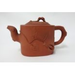 A Yixing teapot, oval shaped with moulding of trailing plant, height 12cm.