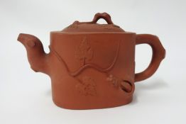 A Yixing teapot, oval shaped with moulding of trailing plant, height 12cm.