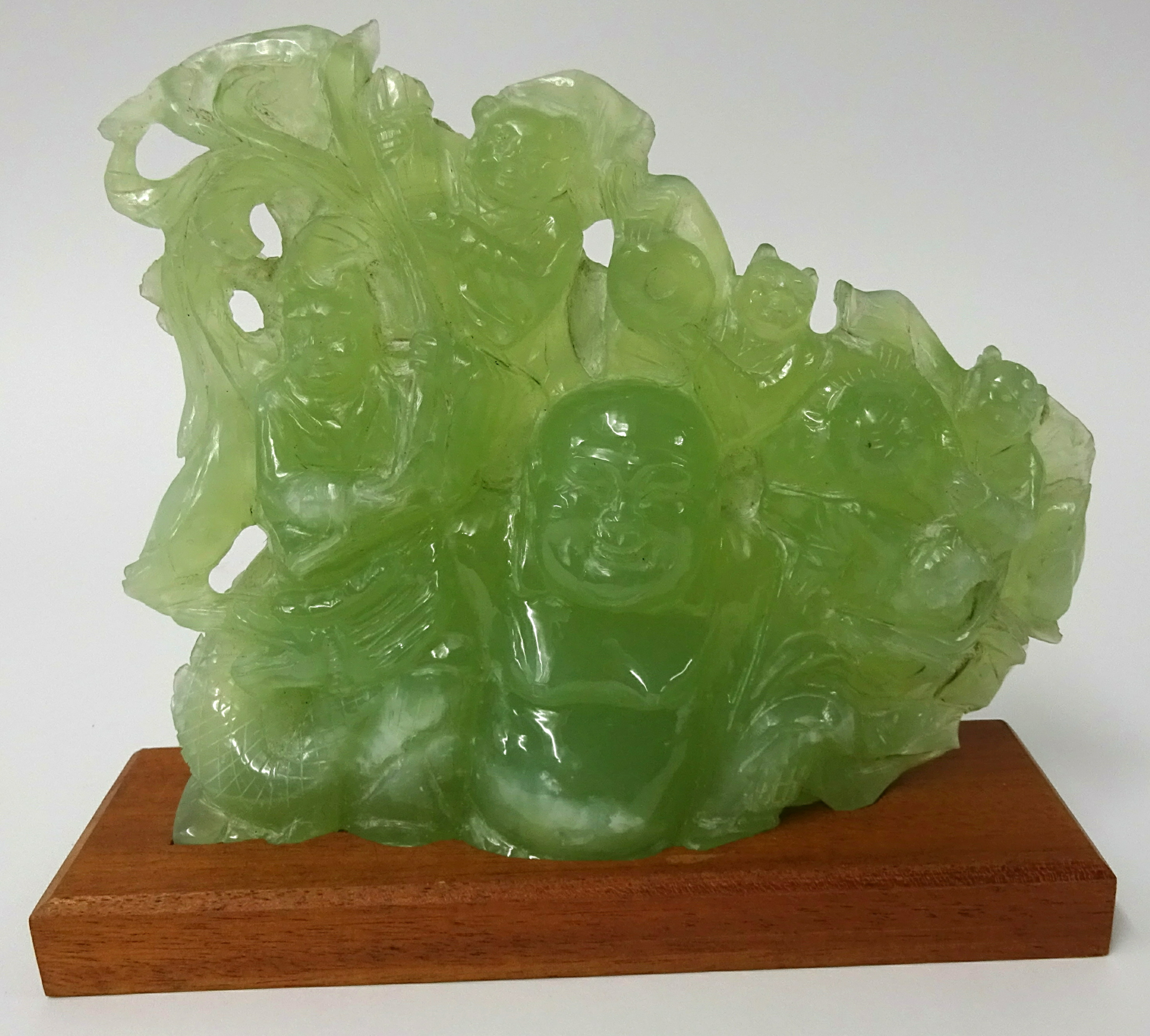 A carved 'jade' group depicting Buddha and laughing monkeys, height 18cm, width 22cm on later