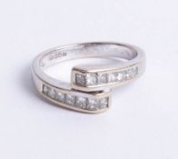 An 18ct white gold and diamond channel set cross over ring, size M.