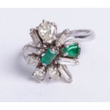 An 18ct white gold emerald and asymmetrical diamond cluster ring, size N.