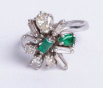 An 18ct white gold emerald and asymmetrical diamond cluster ring, size N.