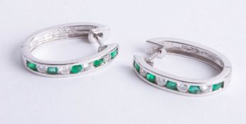 A pair 14ct white gold diamond and emerald hoop earrings.