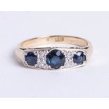 A 9ct gold and platinum seven stone ring, comprising three graduated round cut sapphires, divided