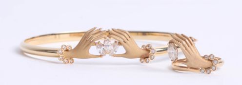 A yellow gold bangle with hands and diamond effects stones and a matching ring, indistinct marks