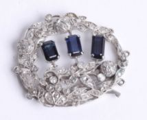 A pretty white gold sapphire and diamond brooch set with three sapphires and an arrangement of