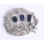 A pretty white gold sapphire and diamond brooch set with three sapphires and an arrangement of