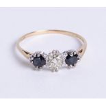 A 9ct gold three stone ring, comprising central old cut diamond with one round cut sapphire set