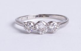 A platinum and diamond set three stone ring, size M.