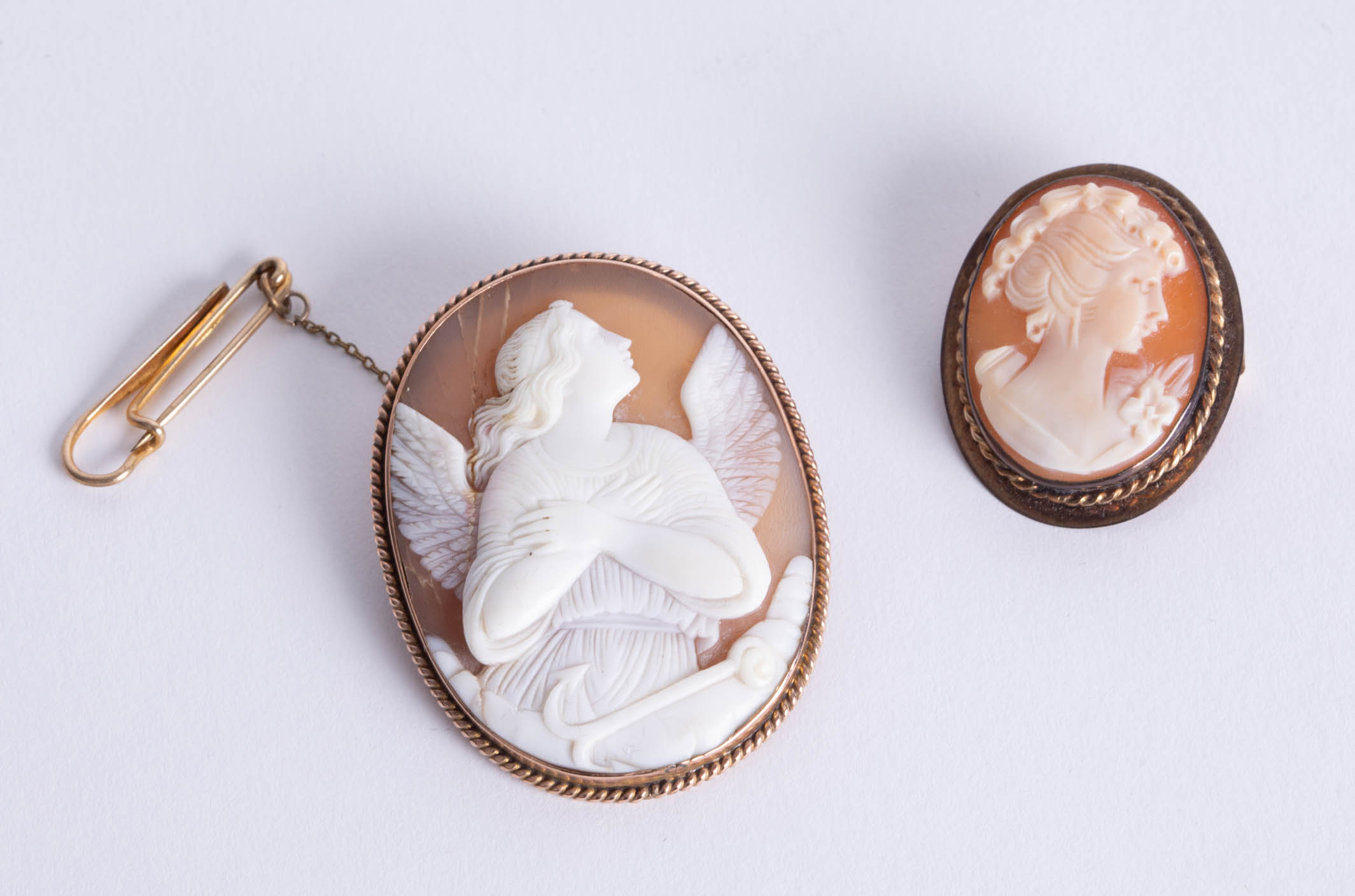 An antique relief carved cameo brooch, depicting angel with anchor, in unmarked yellow metal frame