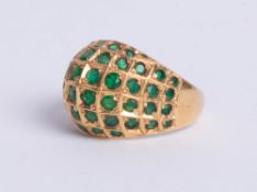 An 18ct yellow domed gold dress ring, comprising six rows of small round cut emeralds graduated to