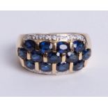 An 18ct Yellow gold band ring, comprising three central rows of oval cut sapphires loop set with an