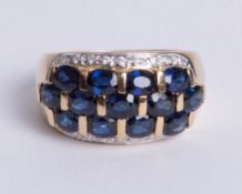 An 18ct Yellow gold band ring, comprising three central rows of oval cut sapphires loop set with an