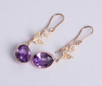 A pair of 9ct yellow gold amethyst and pearl drop earrings, each comprising an oval cut amethyst