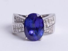 White metal large oval Tanzanite solitaire stone in four claw setting with diamond set crossover