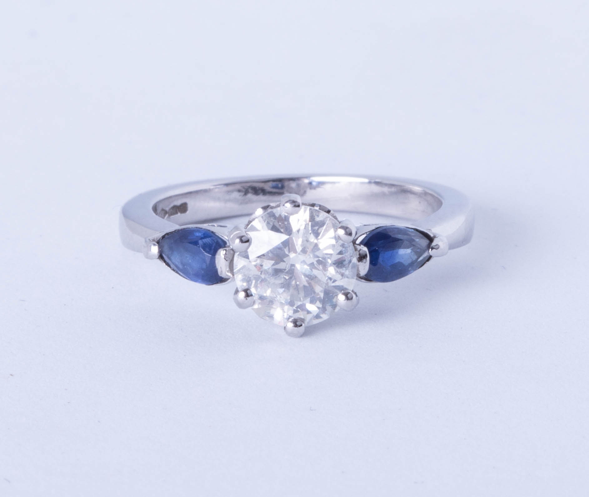 A platinum trilogy ring comprising a central brilliant cut diamond flanked on each side by royal