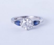 A platinum trilogy ring comprising a central brilliant cut diamond flanked on each side by royal