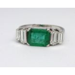 An 18ct emerald and diamond ring, set with baguette cut diamonds in a claw setting, the emerald 7.