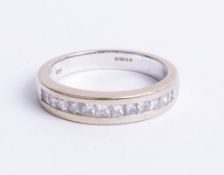 An 18ct white gold and channel set half band diamond eternity ring, finger size M.