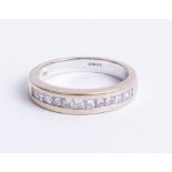 An 18ct white gold and channel set half band diamond eternity ring, finger size M.