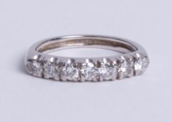 A 14ct white gold half hoop ring. comprising seven round brilliant cut diamonds mounted in a claw