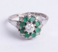A platinum and 18ct gold diamond and emerald cluster ring, size O.