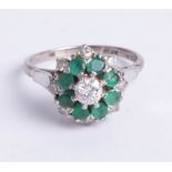 A platinum and 18ct gold diamond and emerald cluster ring, size O.