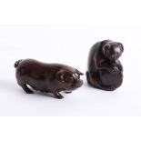 Two Japanese dark wood netsukes, one depicting a pig and the other depicting a dog with a shell.