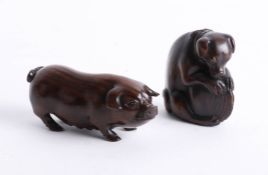 Two Japanese dark wood netsukes, one depicting a pig and the other depicting a dog with a shell.