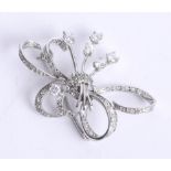 An unmarked probably 18ct white gold diamond ribbon spray brooch, length 39mm.