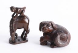 Two Japanese dark wood netsukes, one depicting a dog with crossed legs and one depicting a monkey on