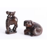 Two Japanese dark wood netsukes, one depicting a dog with crossed legs and one depicting a monkey on