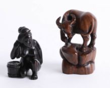 Two Japanese dark wood netsukes, one depicting a woman washing her back and one depicting a horned
