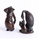 Two Japanese dark wood netsukes, one depicting a bird with its head in a bottle with a dog, and