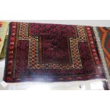 RED GROUND HAND KNOTTED WOOLEN 'OLD BALUCHI' RUG WITH TASSELLED ENDS (124CM X 90CM)