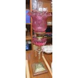 BRASS OIL LAMP WITH CRANBERRY GLASS RESERVOIR AND SHADE, THE REEDED COLUMN WITH A CLEAR GLASS