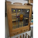 LIGHT OAK WALL MOUNTED CABINET WITH STAINED LEADED GLASS DOOR AND TWO DRAWERS BENEATH